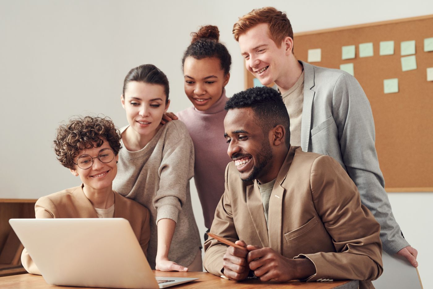 Small agency team huddled around a laptop reviewing pitch deck direction